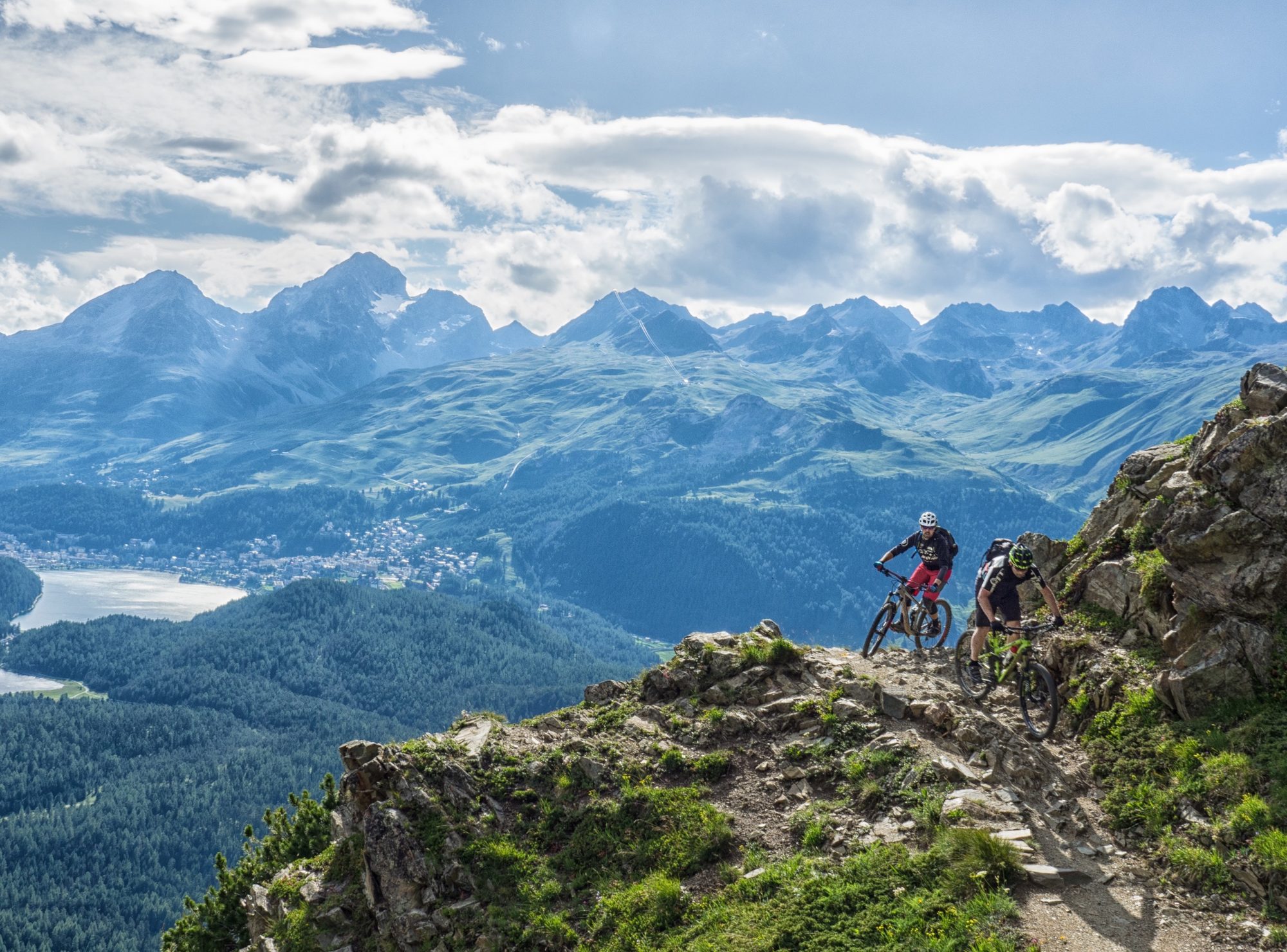 Zwei Mountainbiker auf einem Felstrail hoch über dem Oberengadin